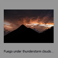 Fuego under thunderstorm clouds at sunset